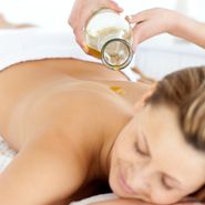 Glad young woman enjoying a back massage with oil in a spa center-1